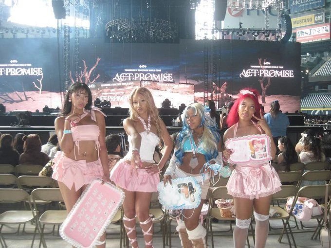 Fans occidentales con vestimentas temáticas y pancartas personalizadas antes de un concierto de TXT (ACT: PROMISE).