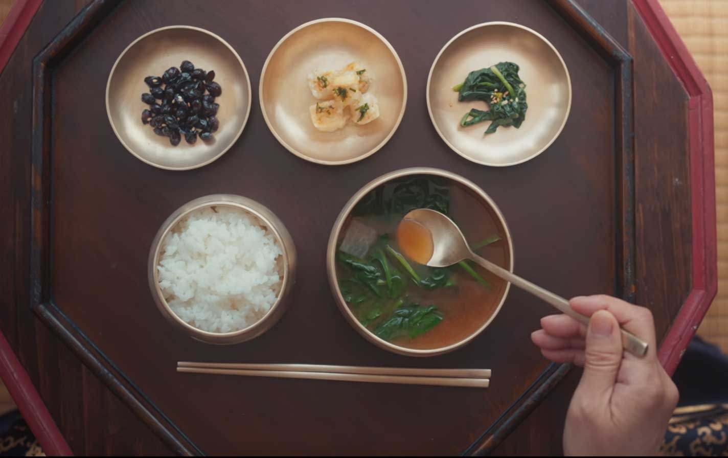 Platillo-Nº4-—-Sopa-de-doenjang-con-espinacas-y-almejas Dos lightsticks ARMY Bomb de BTS sostenidos en alto durante un concierto, con el escenario iluminado al fondo.